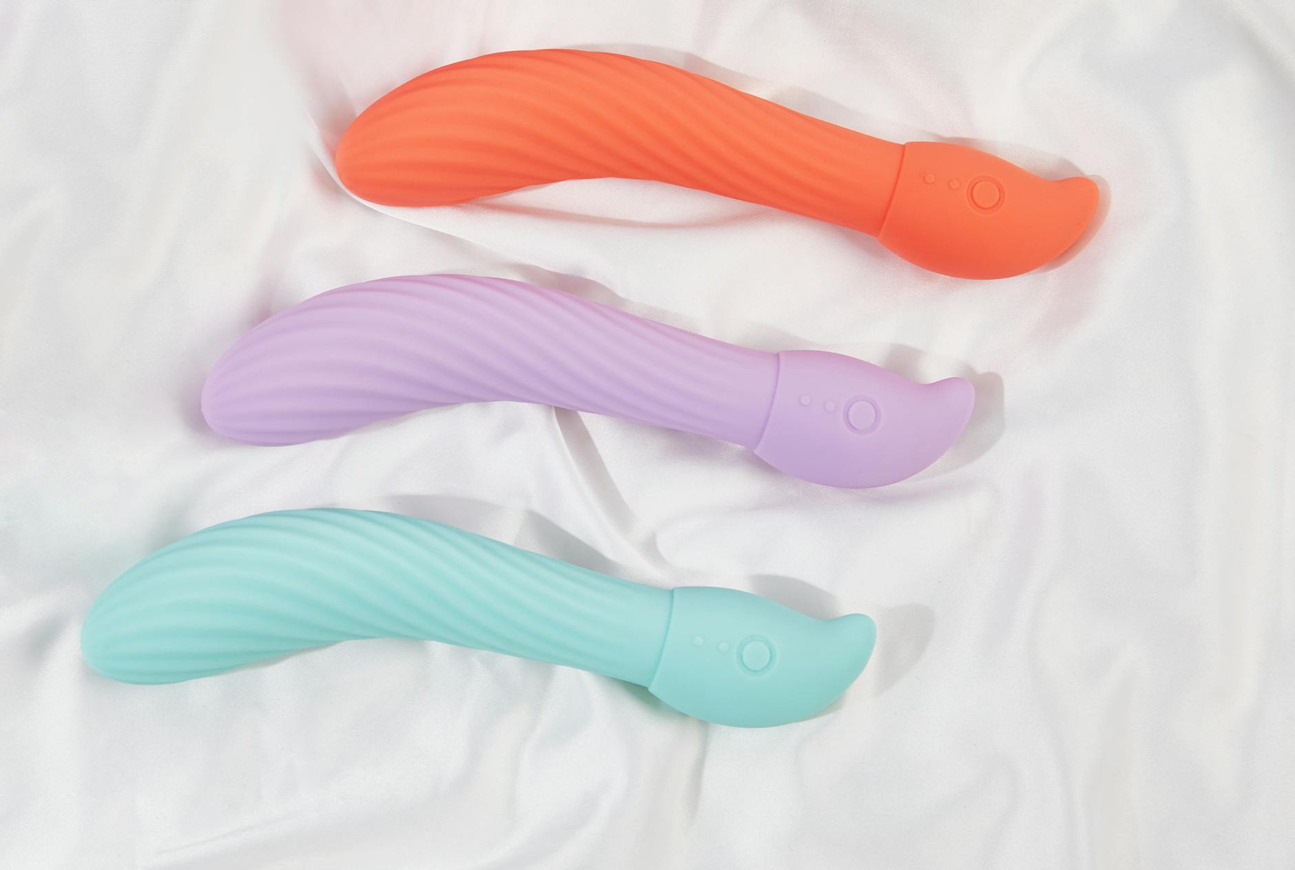 A stylish teal vibrator on smooth white silk fabric, representing personal pleasure and self-care