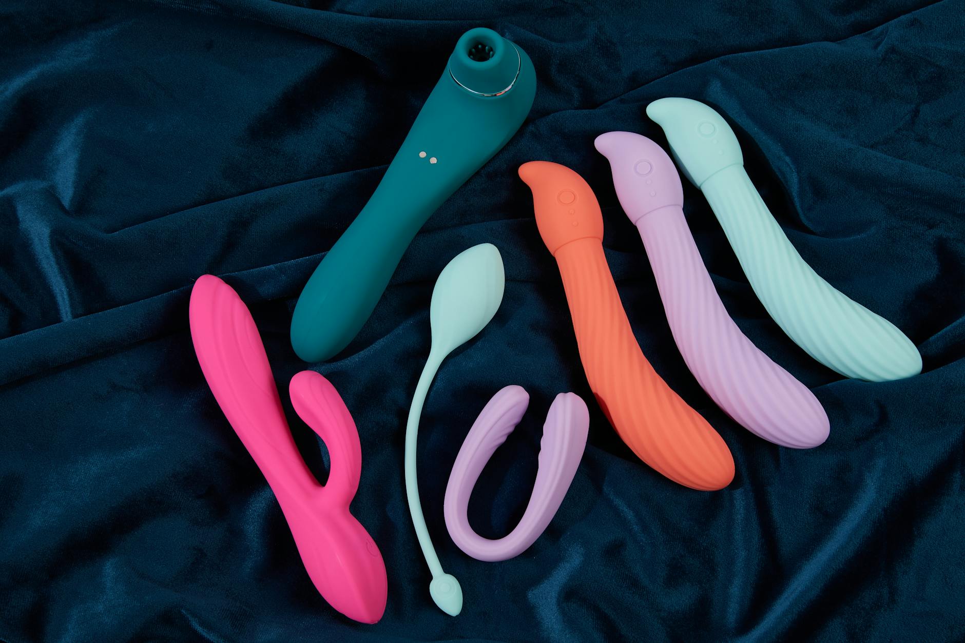 Collection of colorful silicone vibrators arranged on fabric, representing diverse pleasure options