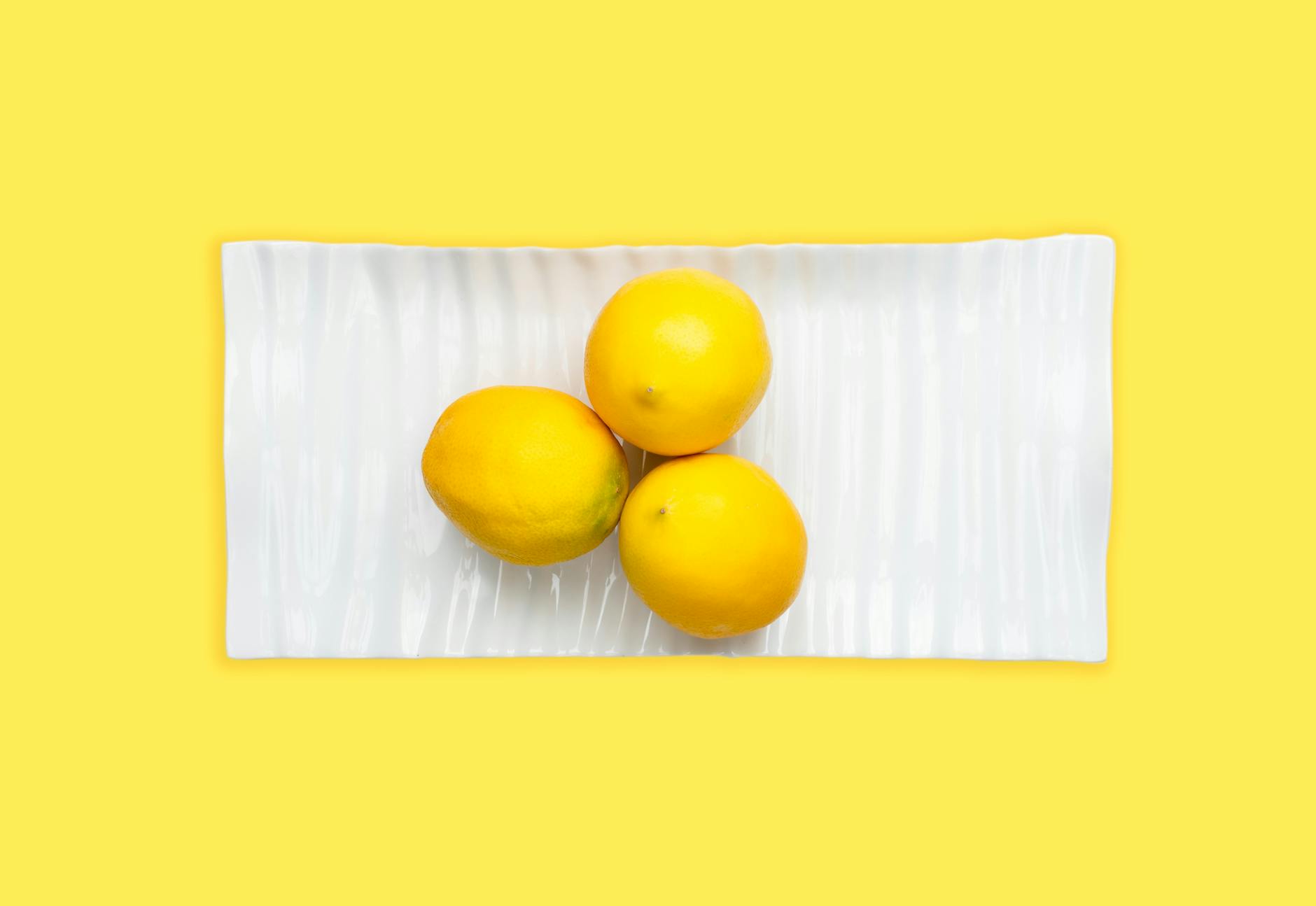 Fresh lemons on a white plate symbolizing the refreshing innovation of lemon clitoral vibrators