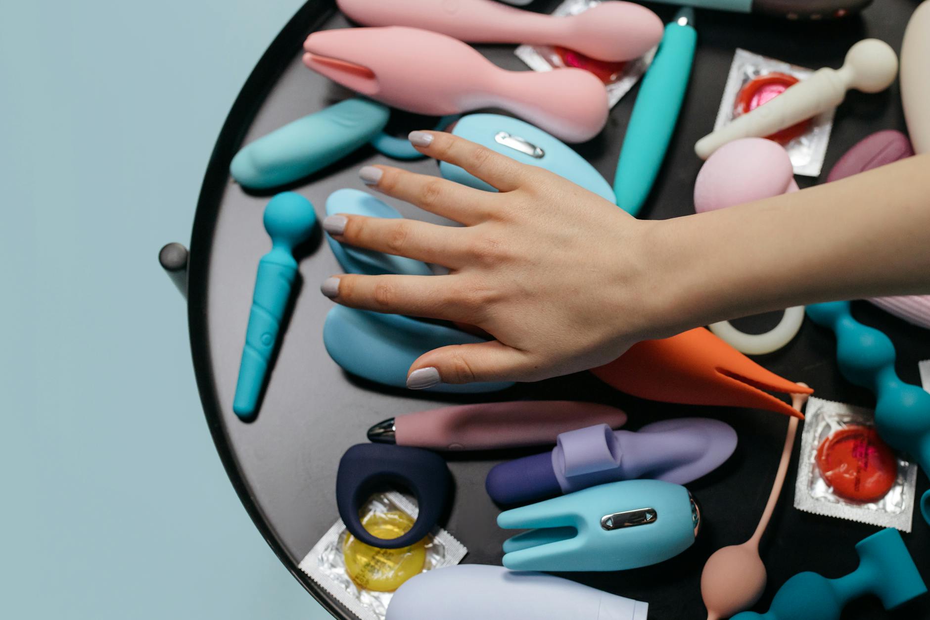 Colorful sex toys arranged on a bright yellow surface showcasing diversity in clitoral stimulation methods