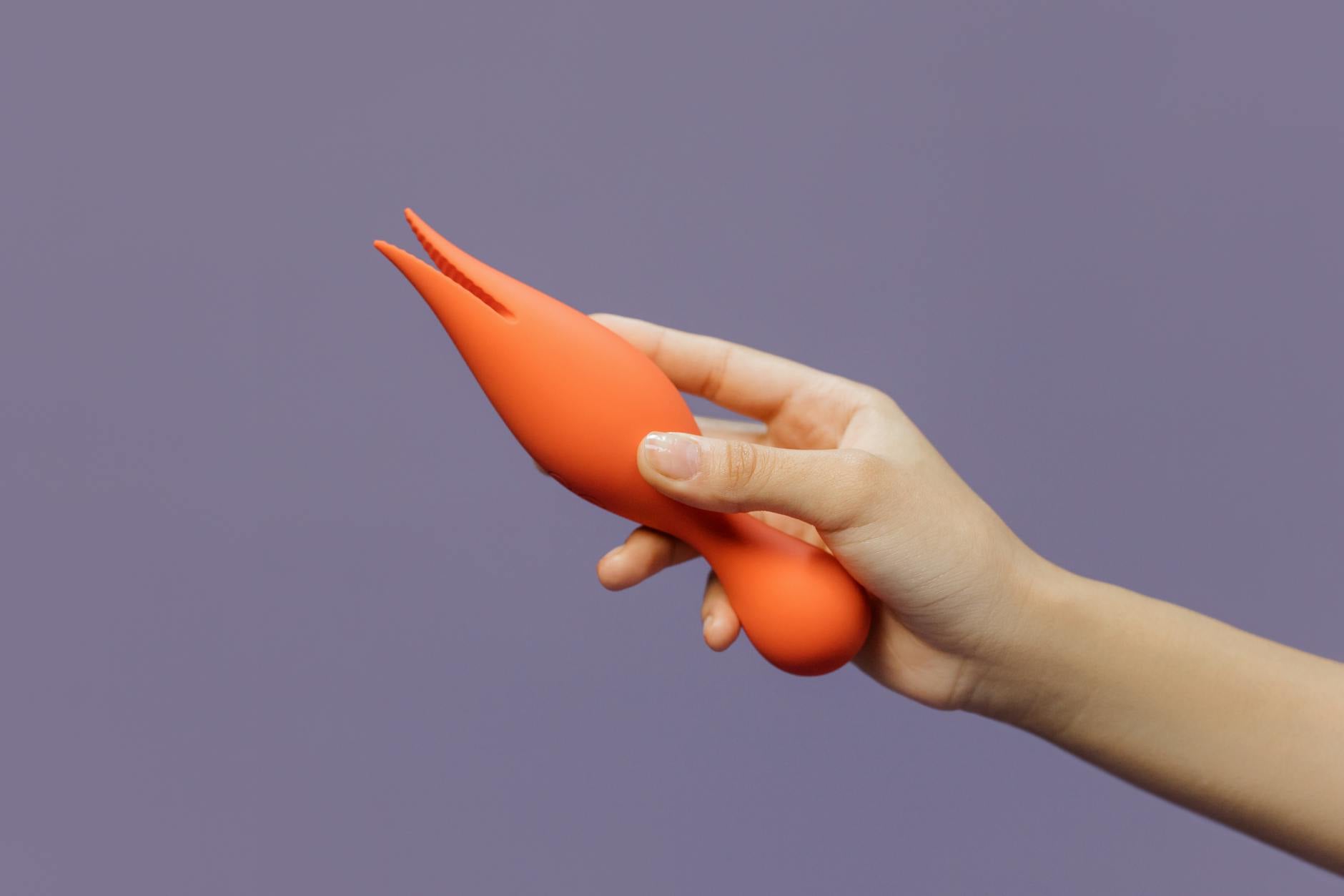 Close-up of a hand holding a vibrator against a minimalistic purple backdrop, symbolizing self-care after stress.