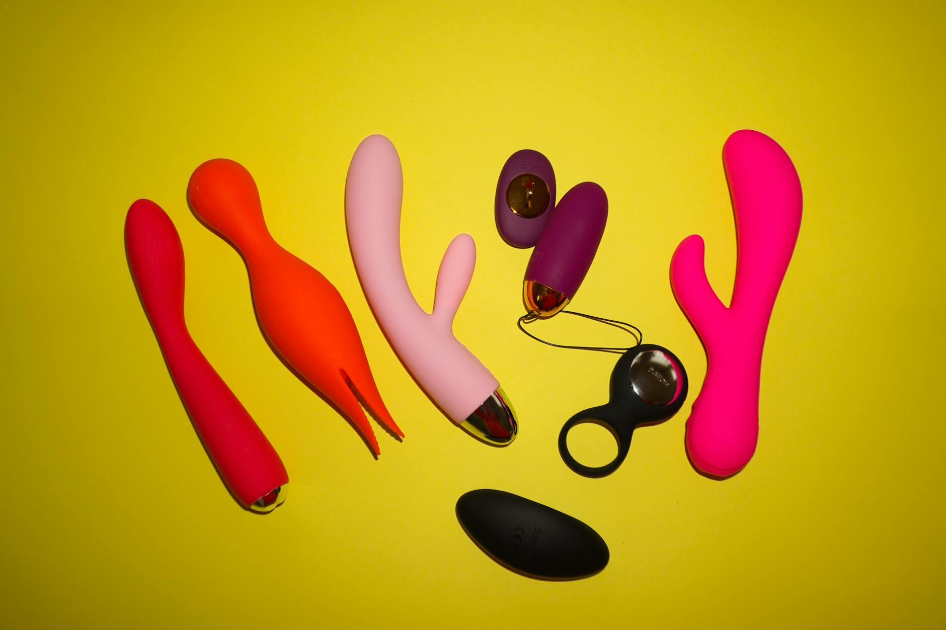 A blue silicone clitoral vibrator held in hand against a solid purple background.